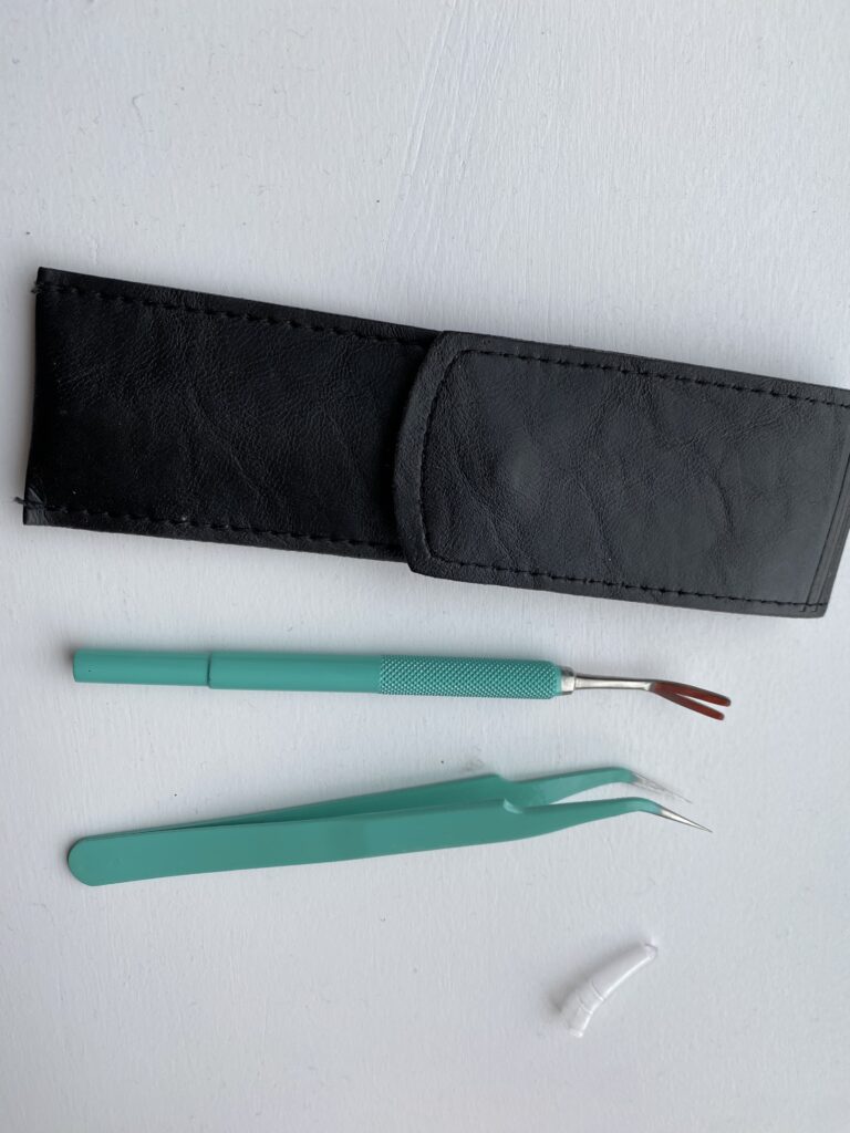 Black pocket and green and stainless steel instruments used for tick removal