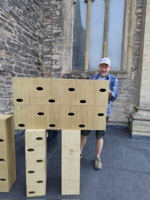 Man with wooden structures with holes for swifts