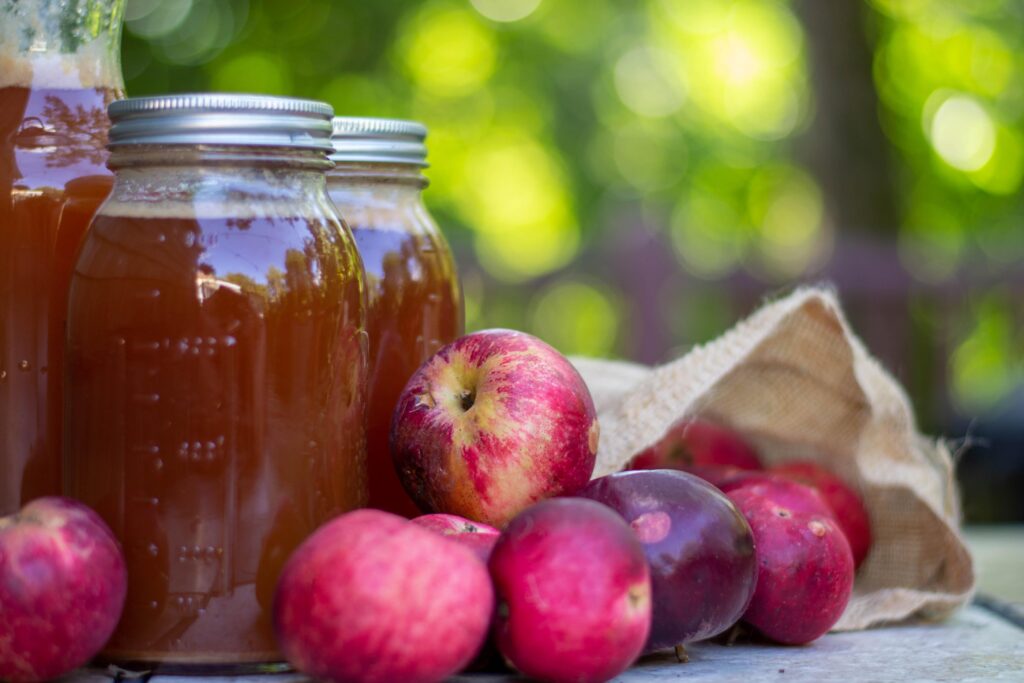 red apples and home made cider in glass jars