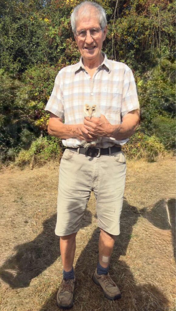 Man in shorts holding a small white owlet
