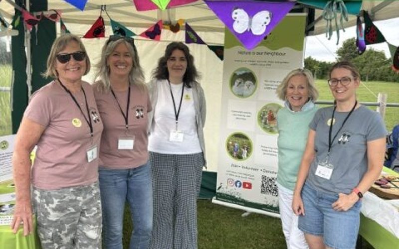 Group of females volunteering at a carnival beneath a green gazebo