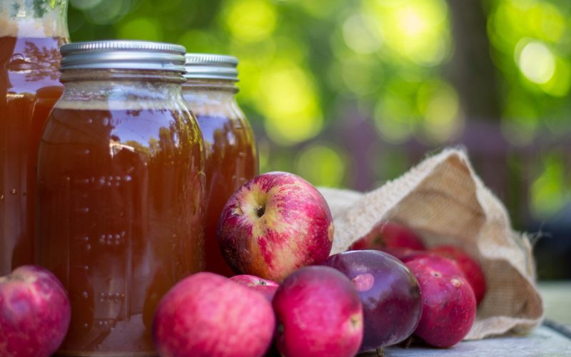 red apples and home made cider in glass jars